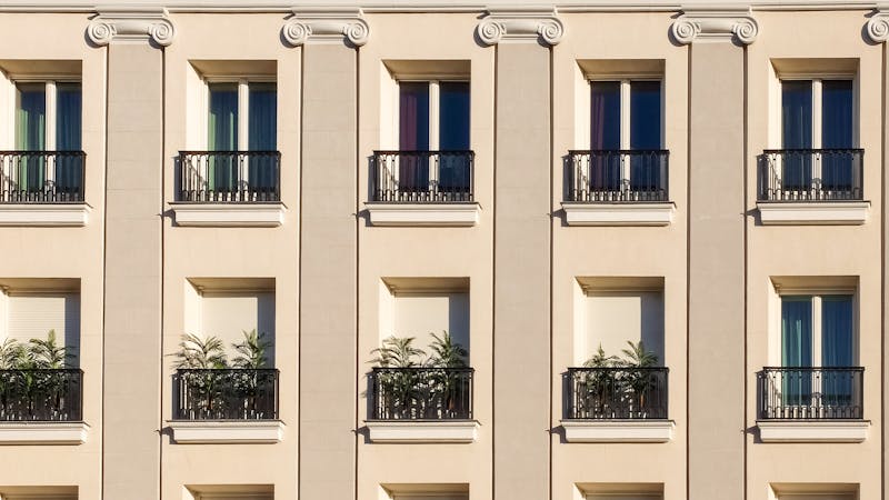 Fachada de edificio residencial con múltiples ventanas y balcones típico de comunidad de propietarios